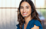 Customer support woman smiling and looking at camera. Portrait of happy customer support phone operator at call center wearing headset. Cheerful executive at your service working at office.